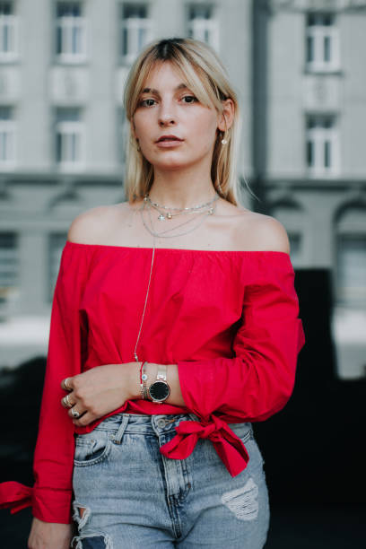Pretty young woman leaning on the windows. Beautiful young fashion blogger posing and looking at camera. Young woman looking at camera.
