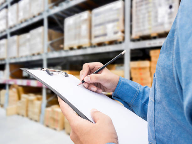 istock Man checking  list on clipboard in a warehouse 825658380