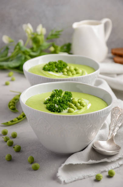istock Green pea soup in bowls on grey concrete or stone background 825663242