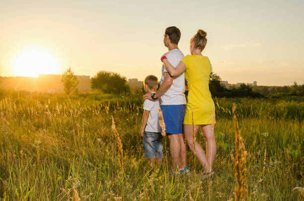 istock happy family standing outdoors on the field embracing 825667004