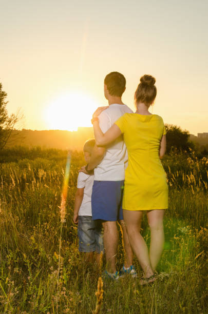 istock happy family standing outdoors on the field embracing 825667038
