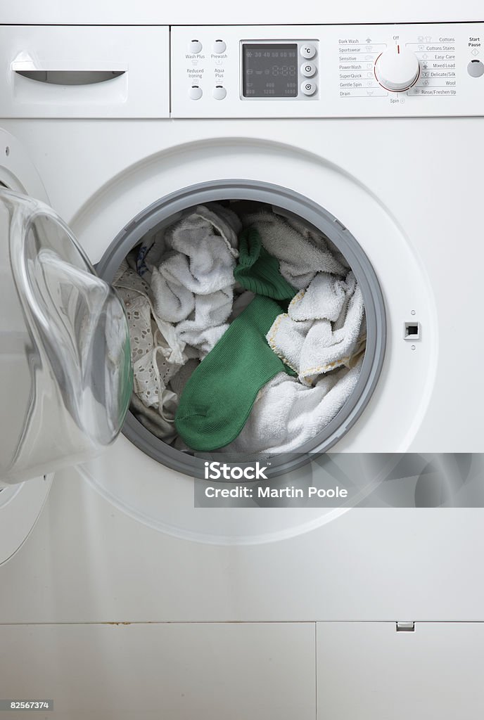 white washing in machine one green sock  Washing Machine Stock Photo