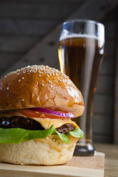 istock Burger with glass of beer on chopping board 825695460