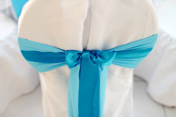 Beautiful fabric bow on the chair. Wedding restaurant for marriage. White decor for bride and groom. Colorful decoration for celebration. Beauty bridal interior