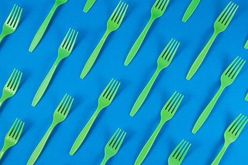 Above view of green colored forks on blue pastel background.
