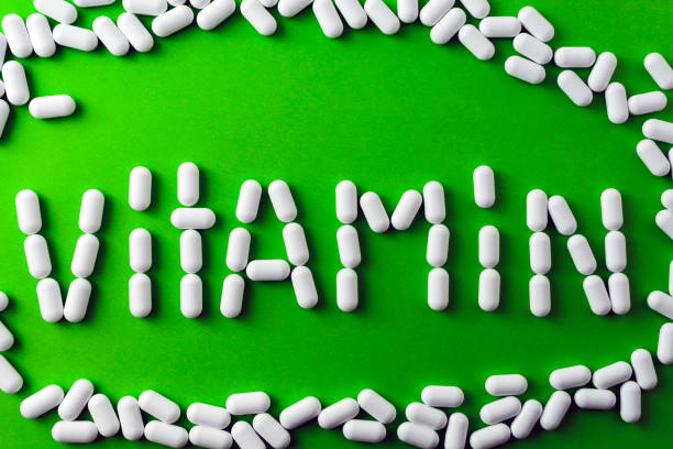 istock text - vitamins - of white pills, tablets on a green background, around pilule. 825704650