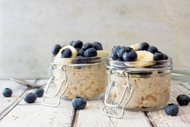 Overnight oats with blueberries and bananas on a white wood background