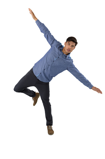 Full length of businessman with arms outstretched balancing while standing against white background