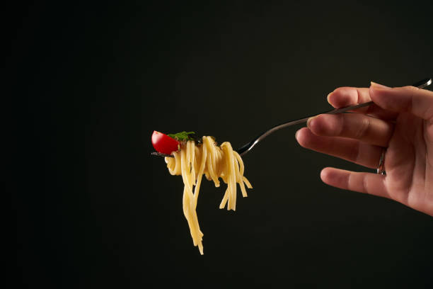 istock Spaghetti on a fork. Girl keeping fork with italian spaghetti 825718426
