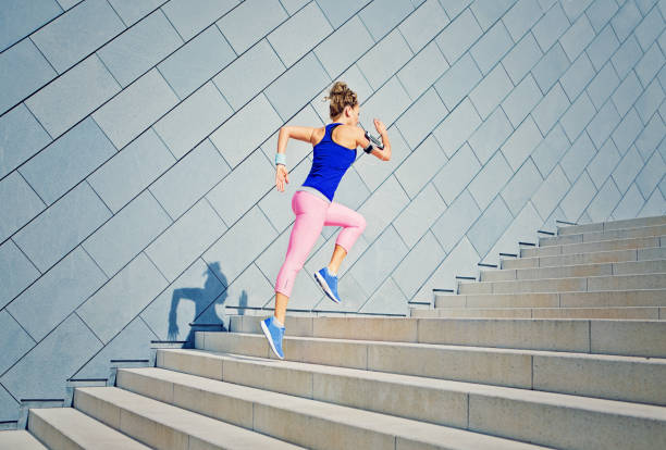 chica es runing en la ciudad de las escaleras y escuchar la música - jumping women running vitality fotografías e imágenes de stock