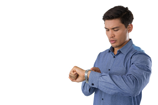 Young businessman looking at time while standing against white background