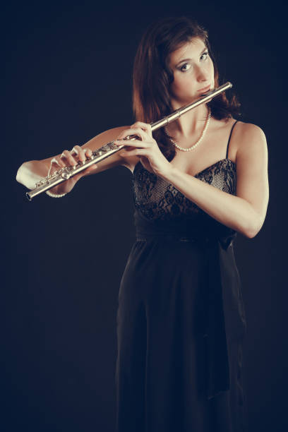 istock Woman playing transverse flute on black. 825729602