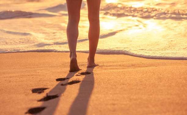 Walking on the beach Close up image of a woman walking on the beach at sunset time. walking beach women sadness stock pictures, royalty-free photos & images