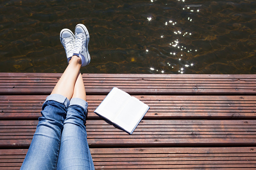Woman relaxing lake side with a book by her side.