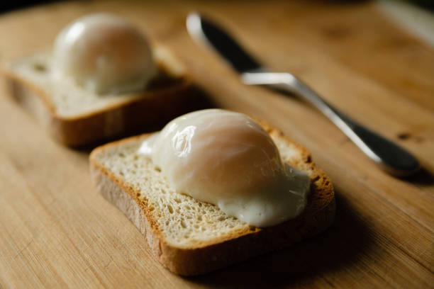 Soft boiled sous vide eggs on toast on a bamboo cutting board