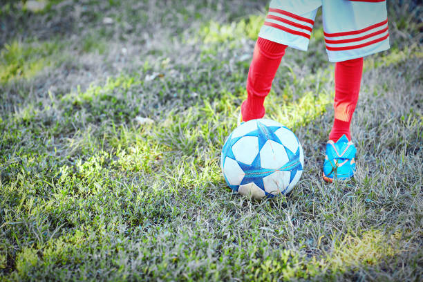 istock Boy in football uniform on grass with ball 825742806