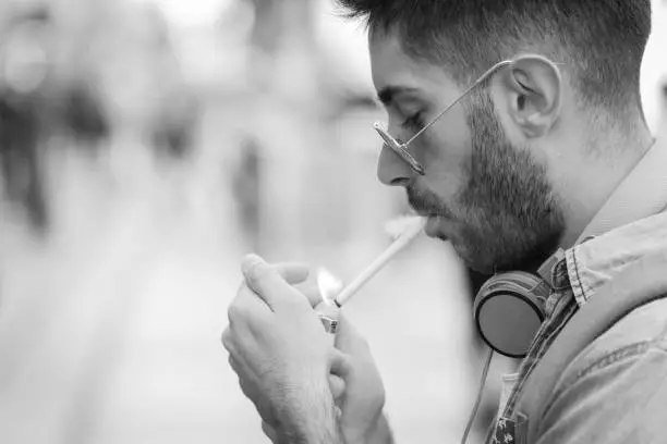 Photo of Man is lighting up a cigarette outdoors.