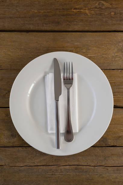 istock White plate with cutlery and napkin on table 825751752