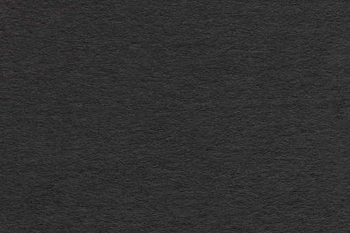 Texture of old dark gray paper closeup. Structure of a dense cardboard. The black background.