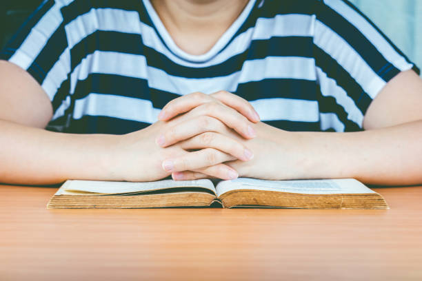 istock Woman hands praying with a bible on wooden table 825761516