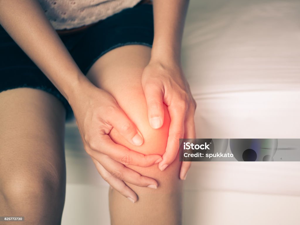 Black and white of young woman massaging her painful knee, Medical and health care concept. Knee Stock Photo