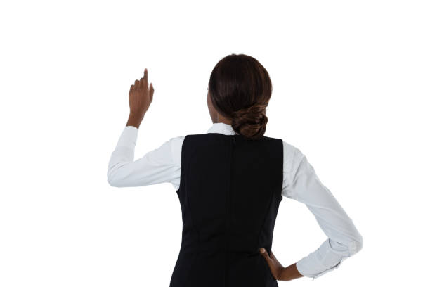 Rear view of businesswoman with hand on hip using invisible interface Rear view of businesswoman with hand on hip using invisible interface against white background black woman hair bun stock pictures, royalty-free photos & images