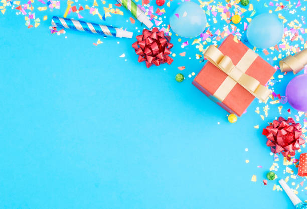 Red gift box various party confetti, balloons, on blue background with border. Flat lay. Colorful celebration pattern