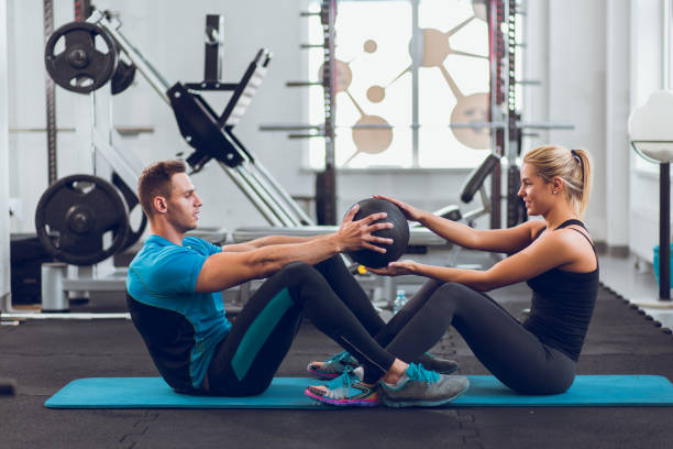 istock Two young sporty people doing sit-ups with medicine ball 825786028