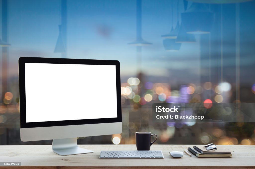 desktop computer on work table and city night background Computer Monitor Stock Photo