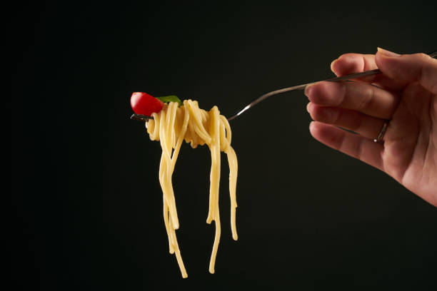 istock Closeup of a spaghetti on a fork. Girl keeping fork with spaghetti. 825796604