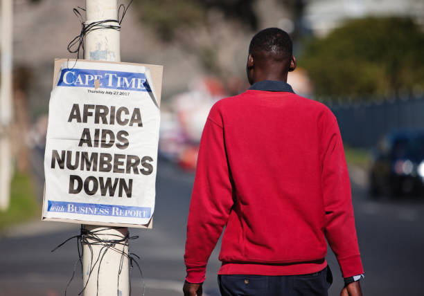 Good news about AIDS: numbers in Africa down Cape Town, South Africa - July 27 2017: Good news about AIDS. A man walks past a news bill saying "Africa AIDS numbers down" on a lamppost in Cape Town, South Africa. The poster is advertising the Cape Times, a local daily newspaper. aids walk stock pictures, royalty-free photos & images