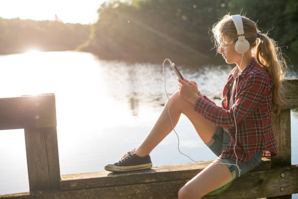 istock Girl sitting at the lake using her mobile 825810690