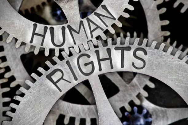 Macro photo of tooth wheel mechanism with HUMAN RIGHTS letters imprinted on metal surface