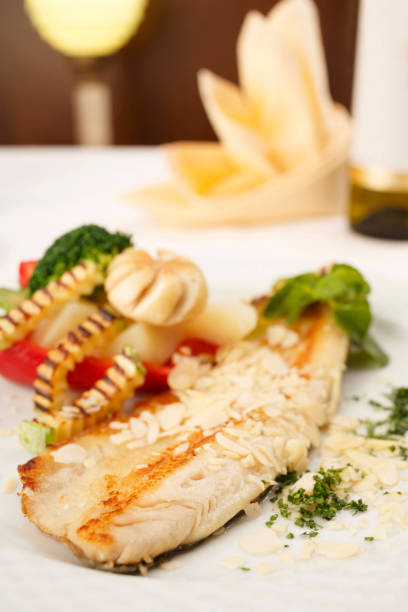 istock Hake fillet with grilled vegetables arranged on a plate, Traditional dish in elegant setting, Selective focus with soft light 825821974