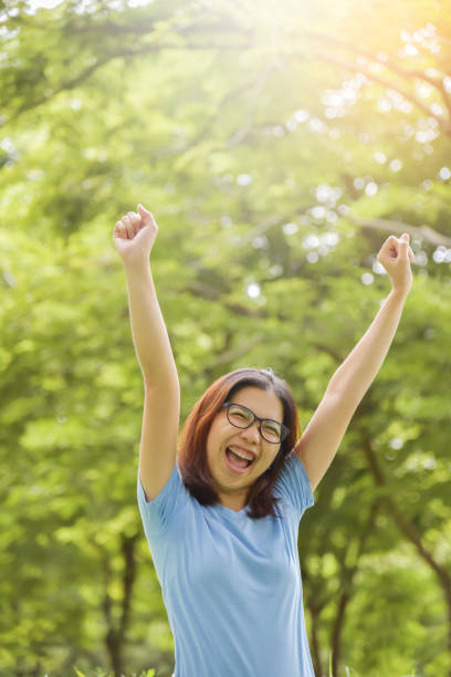 istock Asian woman celebrating with arms raised up. 825822834