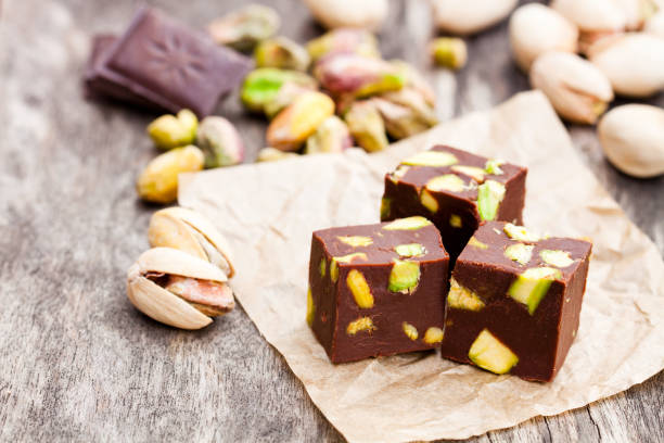 istock Dark  chocolate cubes with pistachios on wooden background 825827994
