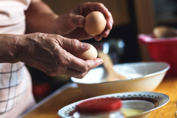 istock Close up of female baker hands preparing eggs for dough. 825828508