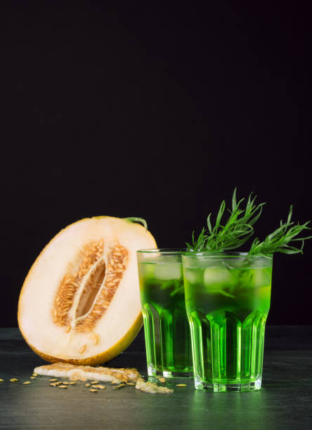 istock Green alcohol cocktails. Cold drinks and a melon on a black background. Drinks with tarragon, ice and sweet melon. Copy space. 825831020