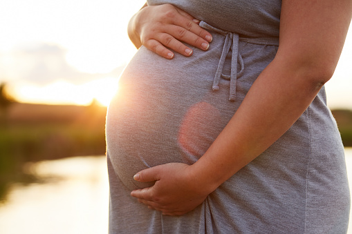 Close up of pregnant woman at sunset