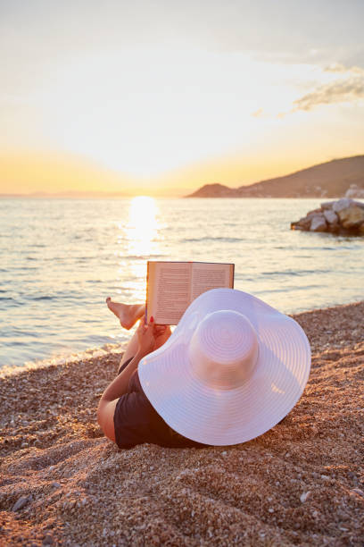 istock Woman reading a book on the beach 825836884