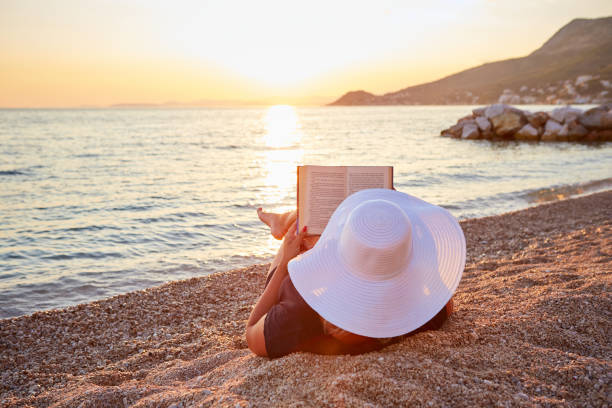 istock Woman reading a book on the beach 825837592