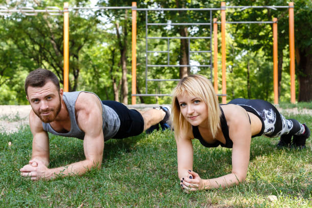 istock Young attractive couple doing exercise plank in a park together. 825846812