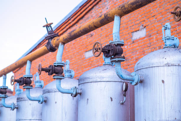 enormi serbatoi di stoccaggio di petrolio, gas e liquidi in un campo all'aperto in fabbrica. pianta petrolifera nel mezzo del mar caspio. valvola di produzione e controllo delle tubazioni per il processo di petrolio e gas. - valve air valve oil field oil foto e immagini stock