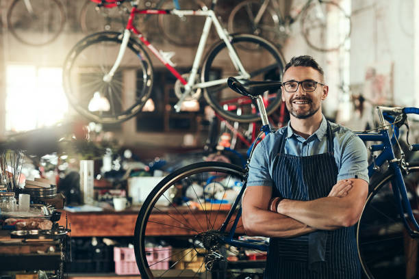 For trusted bicycle repair, I'm your guy Portrait of a mature man working in a bicycle repair shop bicycle shop stock pictures, royalty-free photos & images