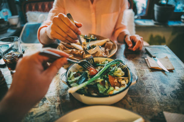 Sharing food Woman taking some of her boyfriend's salad on lunch at a restaurant. ready to eat photos stock pictures, royalty-free photos & images