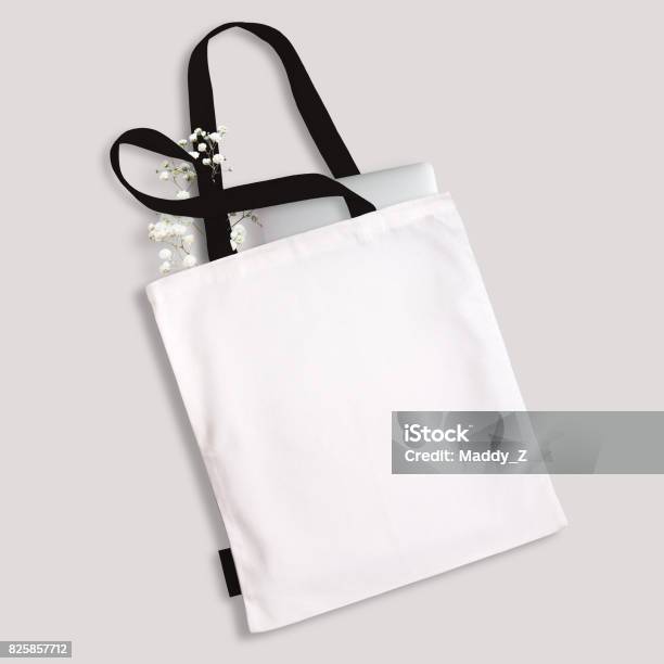 White Blank Cotton Eco Tote Bag With Black Straps And Little Label Laptop And Flowers Inside Design Mockup Stock Photo - Download Image Now