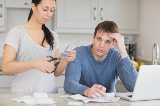 istock Disappointed woman cutting through a credit card 825866410