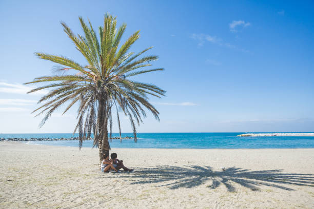 istock Two women relaxing at seaside under the palm 825870648