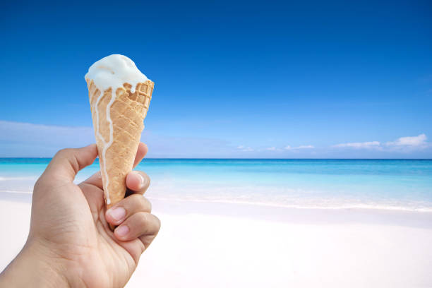 istock hand holding ice cream cone background the sea and blue sky. 825875442