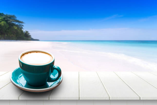 istock Coffee in cup on wooden table with sea view background in summer. 825875670